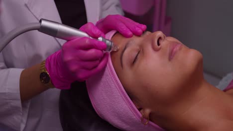 pretty girl getting facial skin care treatment at a spa with a lazer tool