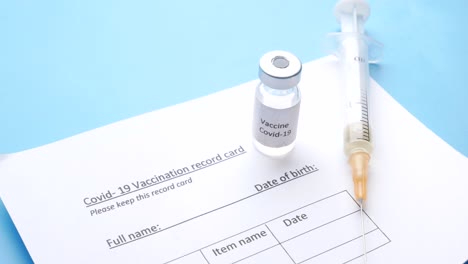 covid-19 vaccination record card and vaccine vial with syringe