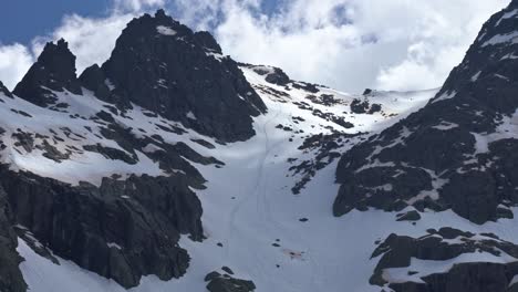 People-freeriding-down-rocky-slope-of-snowy-mountain