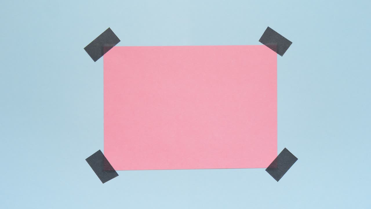 Stop motion of a pink paper card appearing and being taped at four corners on a blue background, leaving clear copy space