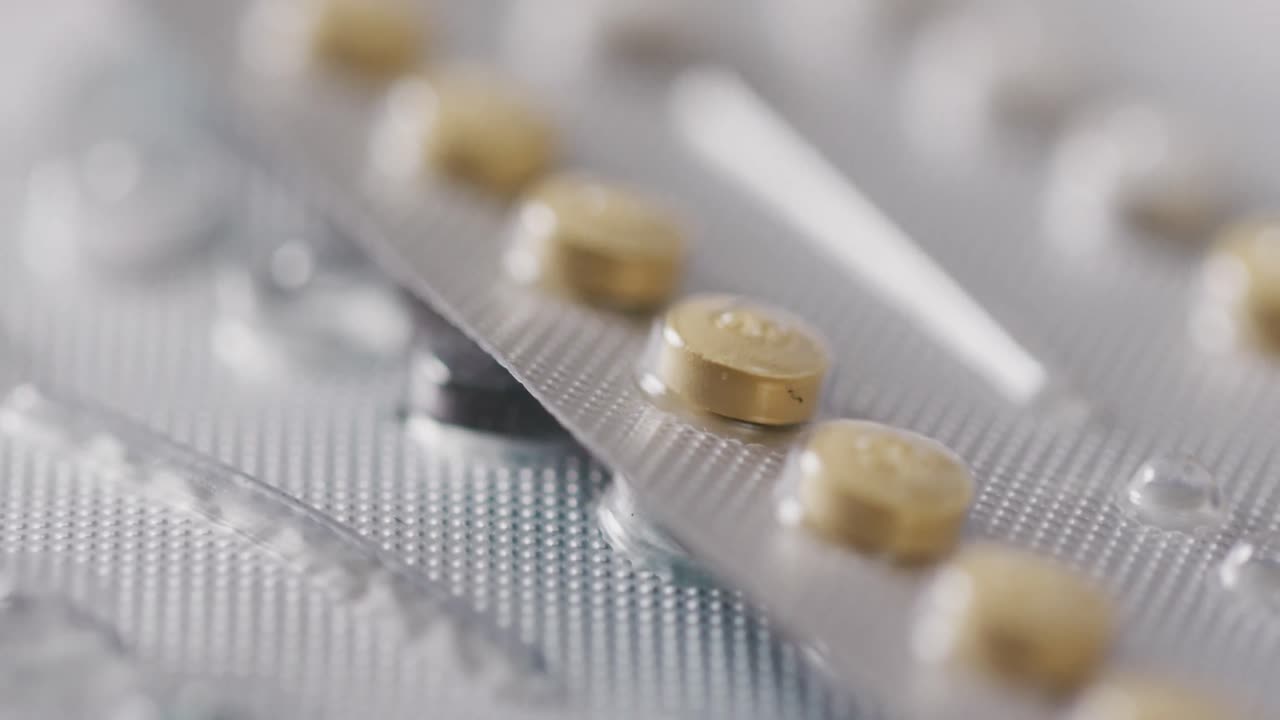 Video of close up of yellow tablets on pink background