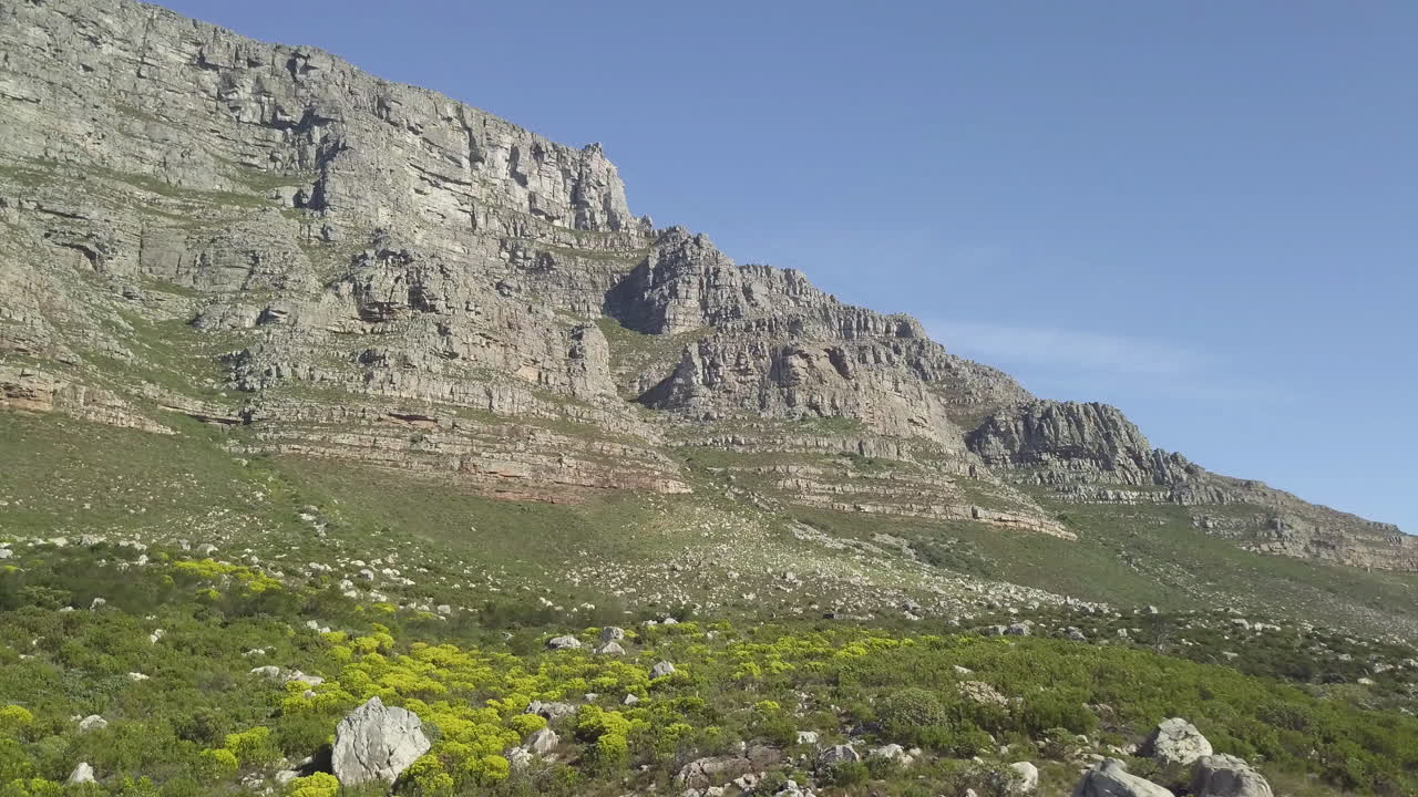 Vista panoramica aerea dal basso con drone della Table Mountain sotto il sole del tardo pomeriggio contro un cielo blu