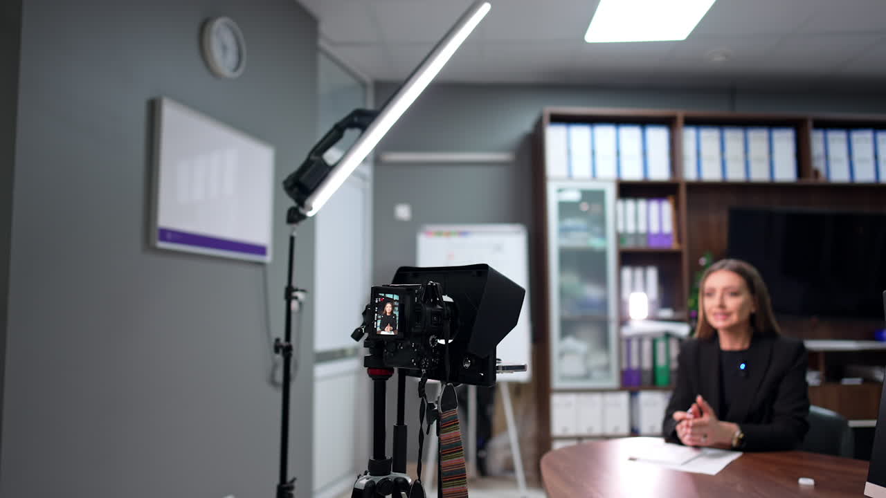 Beautiful Caucasian woman wearing black jacket talks to camera recording a blog. Modern media concept.