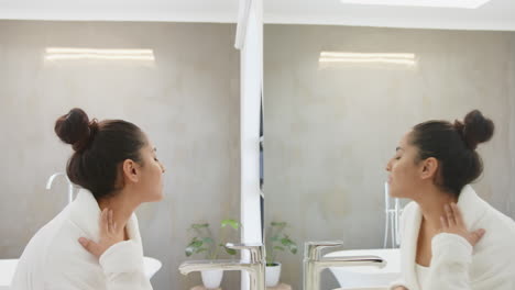 looking in mirror, asian woman in bathrobe touching neck in spa bathroom, at home