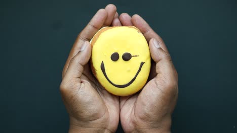 smiling donut held in hands