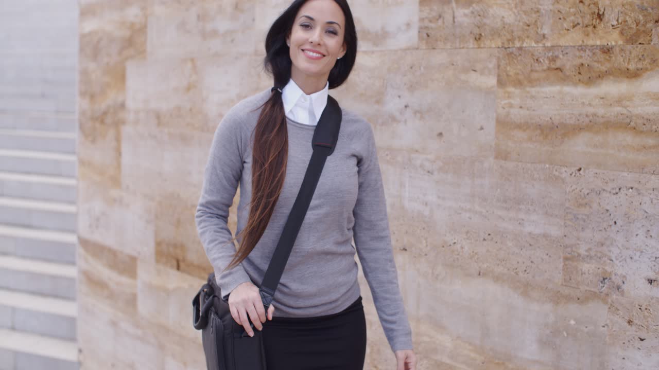 Splendida donna d'affari che passa accanto a un muro