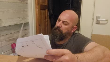 Frustrated-Caucasian-bearded-male-reading-flat-pack-furniture-instructions