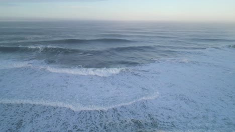 rolling ocean waves near the cliffs of farol nazare, portugal, captured from above
