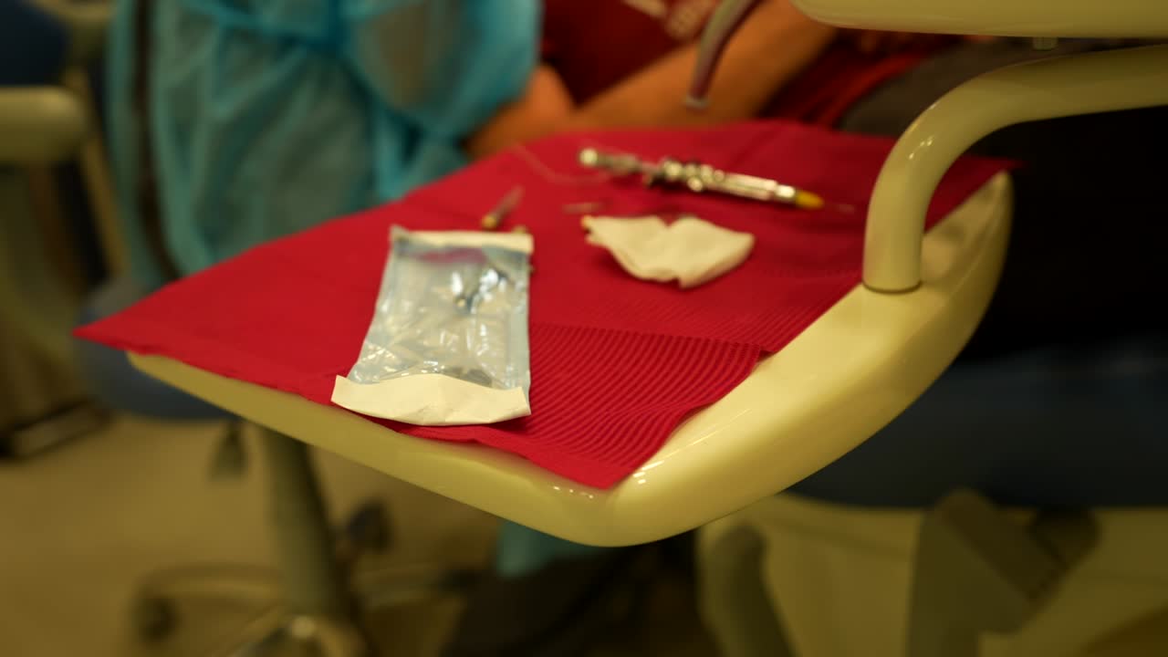 Portable table with sterilized dental tools while a dentist works in background in a dental clinic