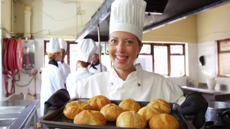 chef femenina sosteniendo el pan en la bandeja de enfriamiento