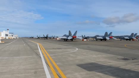 lines of fighter jets sitting on the naval runway, ready to deploy