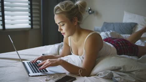 Frau-Im-Schlafanzug-Mit-Laptop-Auf-Dem-Bett