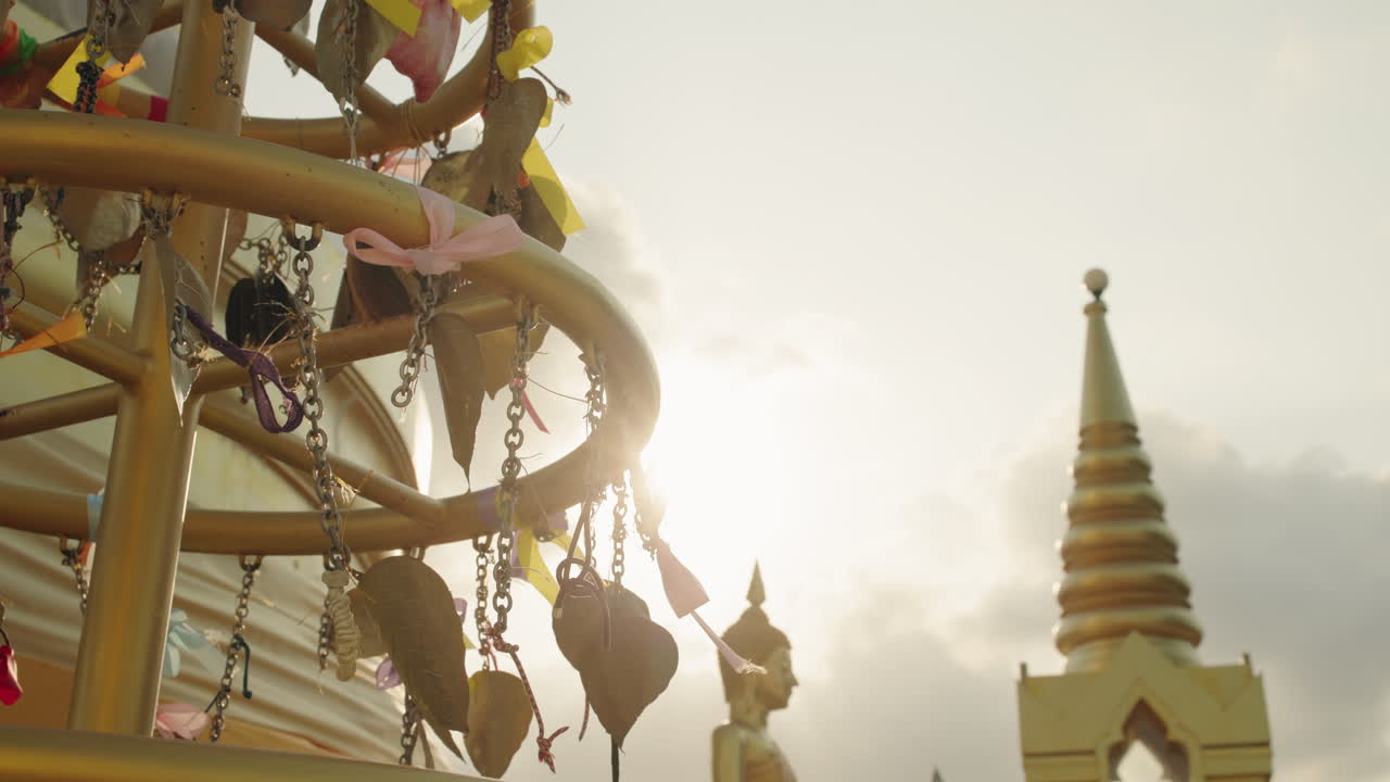 แสงแดดส่องประกายผ่านเครื่องตกแต่งต้นไม้ขอพรในวัด พร้อมเจดีย์ที่พระใหญ่เกาะสมุย