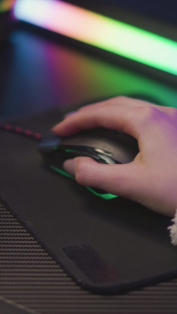 Una mano interagisce con il mouse del computer su un poggiapolsi, illuminato da luci LED colorate. Il focus rimane costantemente sul movimento preciso delle dita e del pollice in vari fotogrammi, evidenziando i dettagli