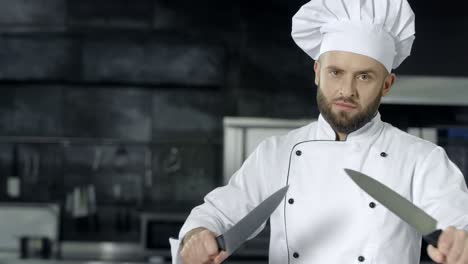 Male-chef-posing-with-crossed-knives.-Chef-sharpening-knives-at-kitchen.