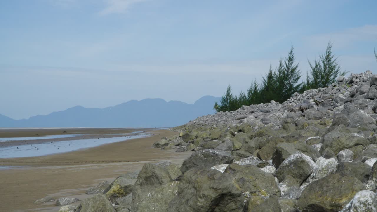 Serene Beach Landscape with Rock Wall and Mountains