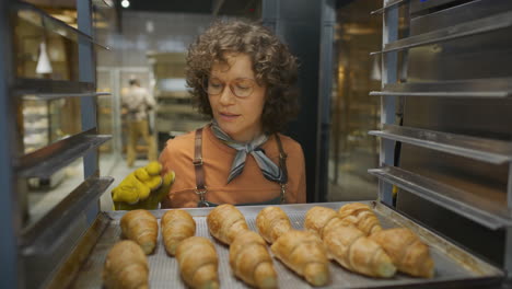 baker placing croissants in a bakery oven