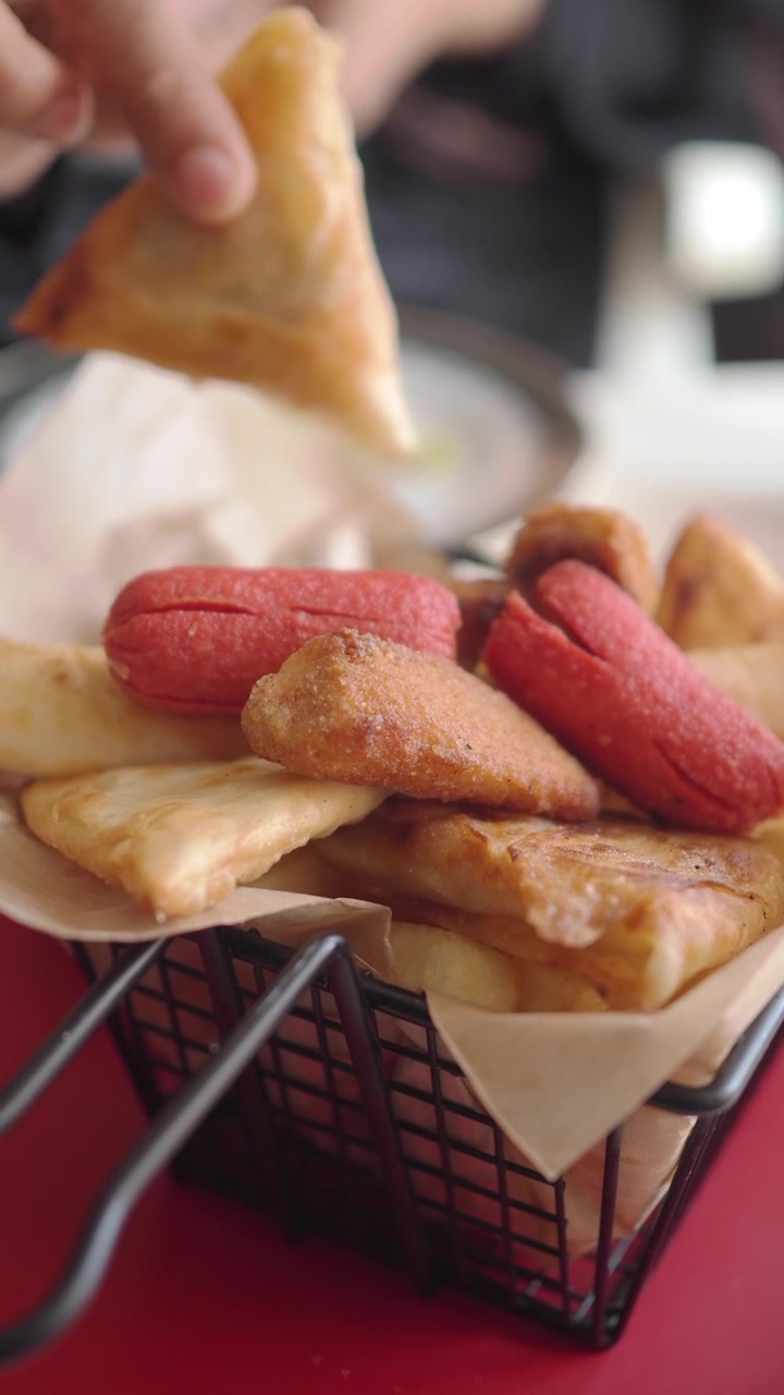 Pegando uma Samosa Frita de uma Cesta de Petiscos