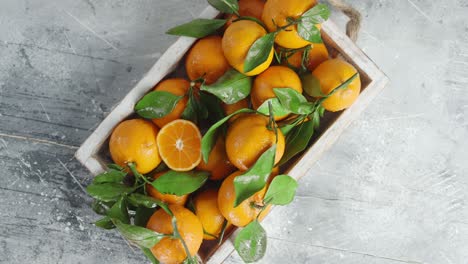 fresh tangerines with leaves in wooden tray rotate slowly.