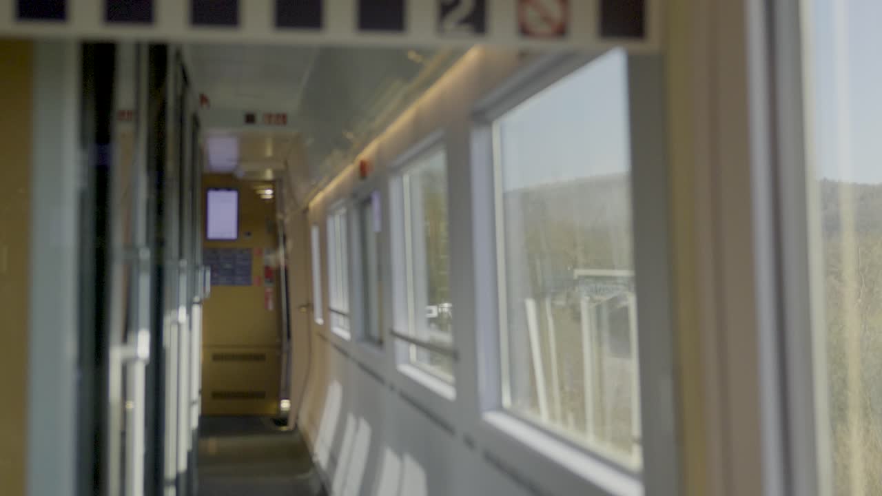 Inside a driving German ICE high-speed train, a view of a modern, sleek corridor