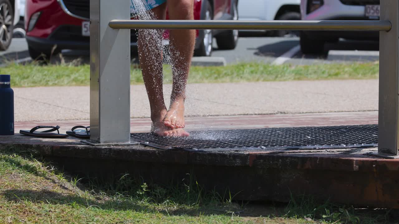 persona enjuagando los pies de arena en la ducha de la playa