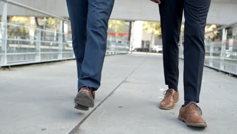 legs of businessmen walking on street