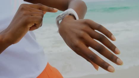 Sección-Media-De-Una-Mujer-Usando-Un-Reloj-Inteligente-En-La-Playa-4k