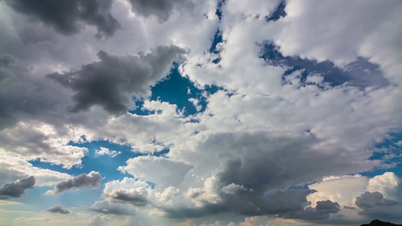Central cloud breaking from instability, opening blue gaps and lit edges over horizon for weather