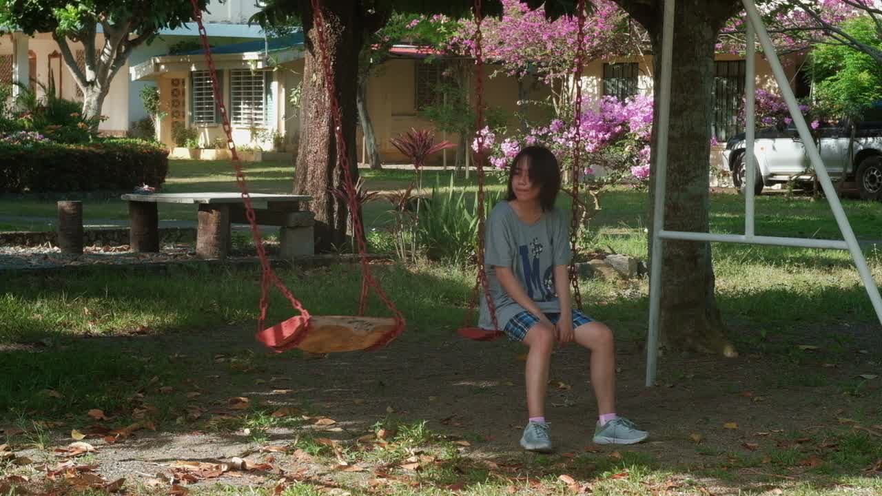 una chica cansada y triste deja de balancearse para mirar un asiento de balanceo vacío a su lado