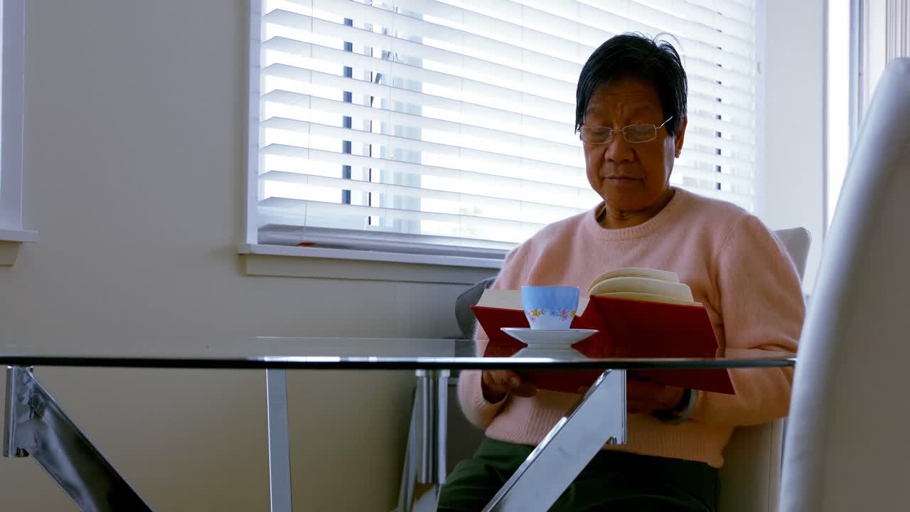 거실에서 책을 읽는 고령 여성