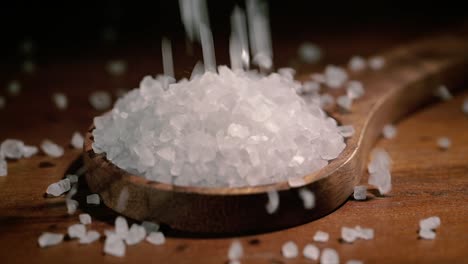 sea salt crystals closeup in wooden spoon on a kitchen table.