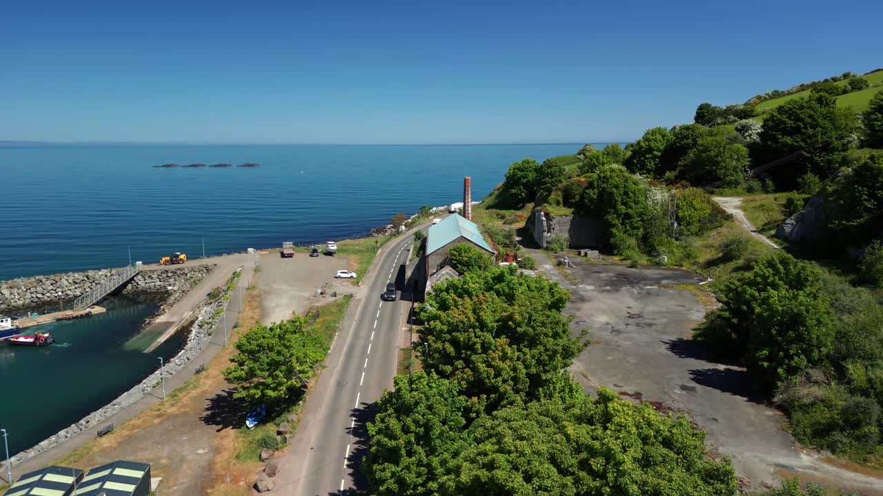 Aerial video of Glenarm Bay and the Glenarm Harbour Chimney, on the Causeway Coastal Route in Northern Ireland, on a bright and sunny day. Filmed in 4K, 60FPS and with Rec709 color.