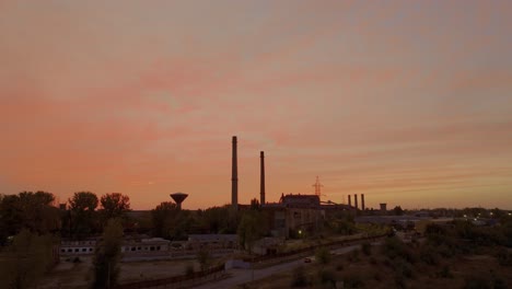 aeria tracking shot of a warm embrace of a stunning sunset illuminates a time-worn industrial area and the silhouettes of towering furnaces stand sentinel 4k50fps cinematic grade