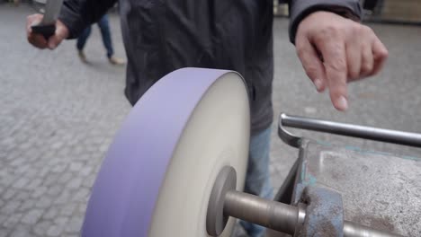 street vendor sharpening a knife on a grinding wheel