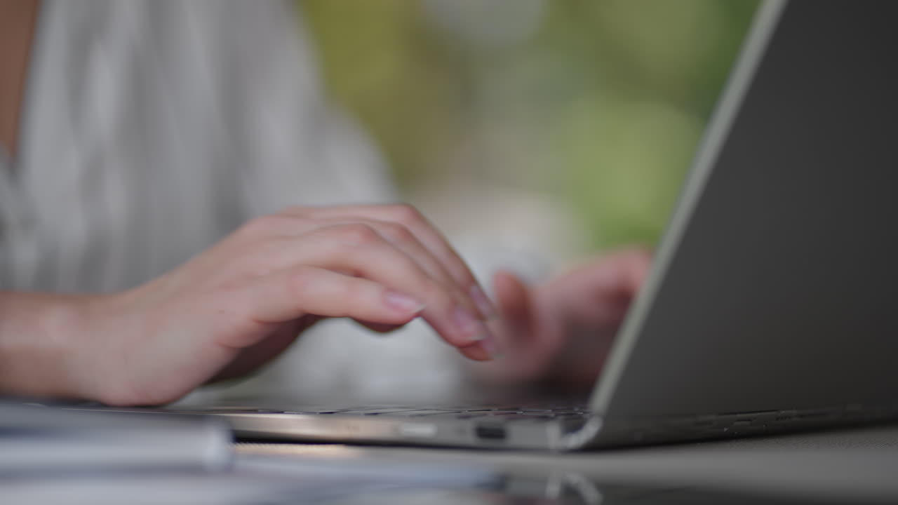 close-up of a woman typing on a laptop keyboard while sitting in a summer cafe. Remote work of a freelancer. Print computer code