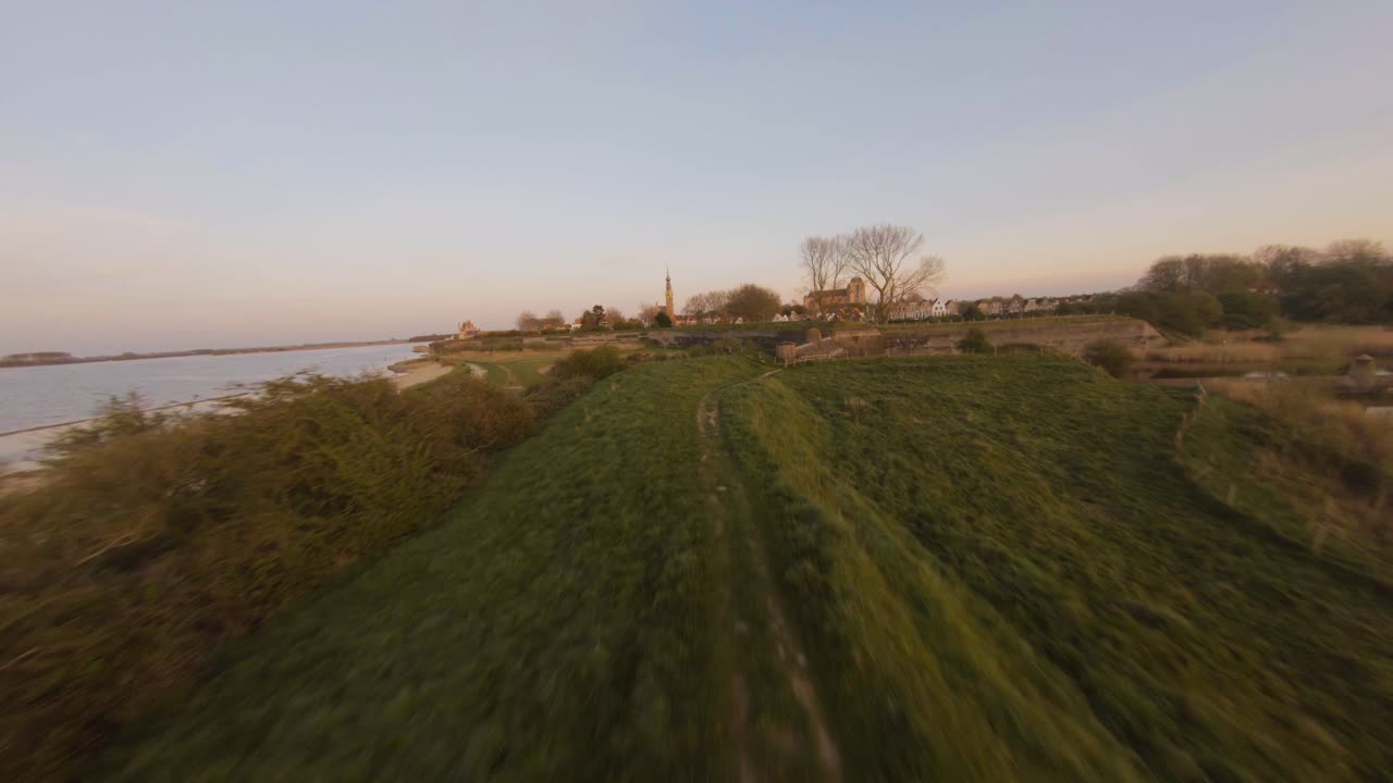 Aerial drone flight along lake by the historic medieval town of Veere in sunset