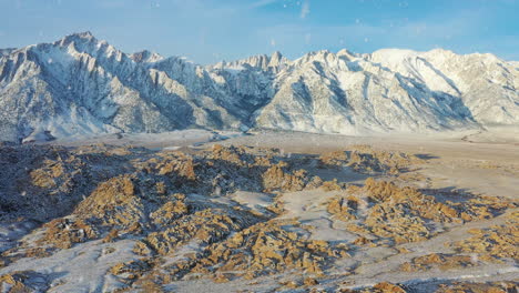 rocky desert and snowy mountain view during snowfall, drone fly towards