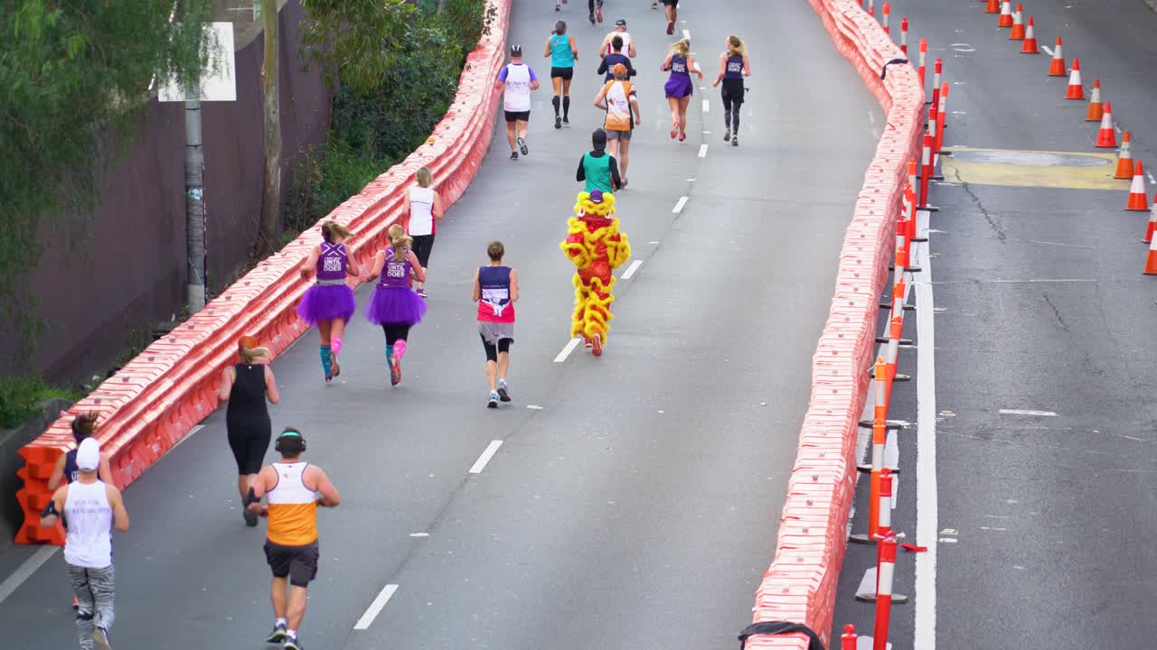 People running in a marathon event with one participant in a lion dance costume
