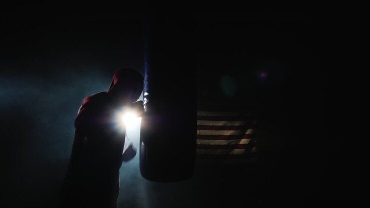 Silueta de luchador Trinity en el gimnasio: golpea un saco de boxeo.