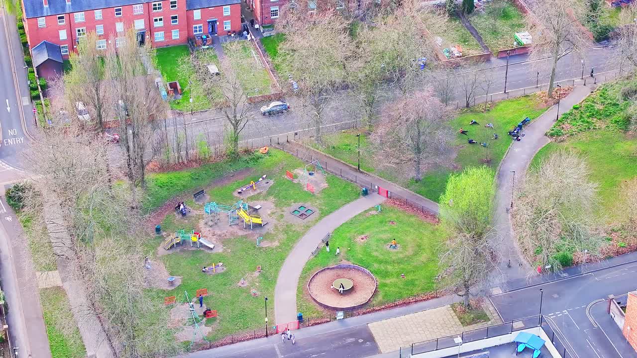 Community playground and green space of Devonshire Green lies among surrounding residential streets in central Sheffield, England, captured in static aerial shot