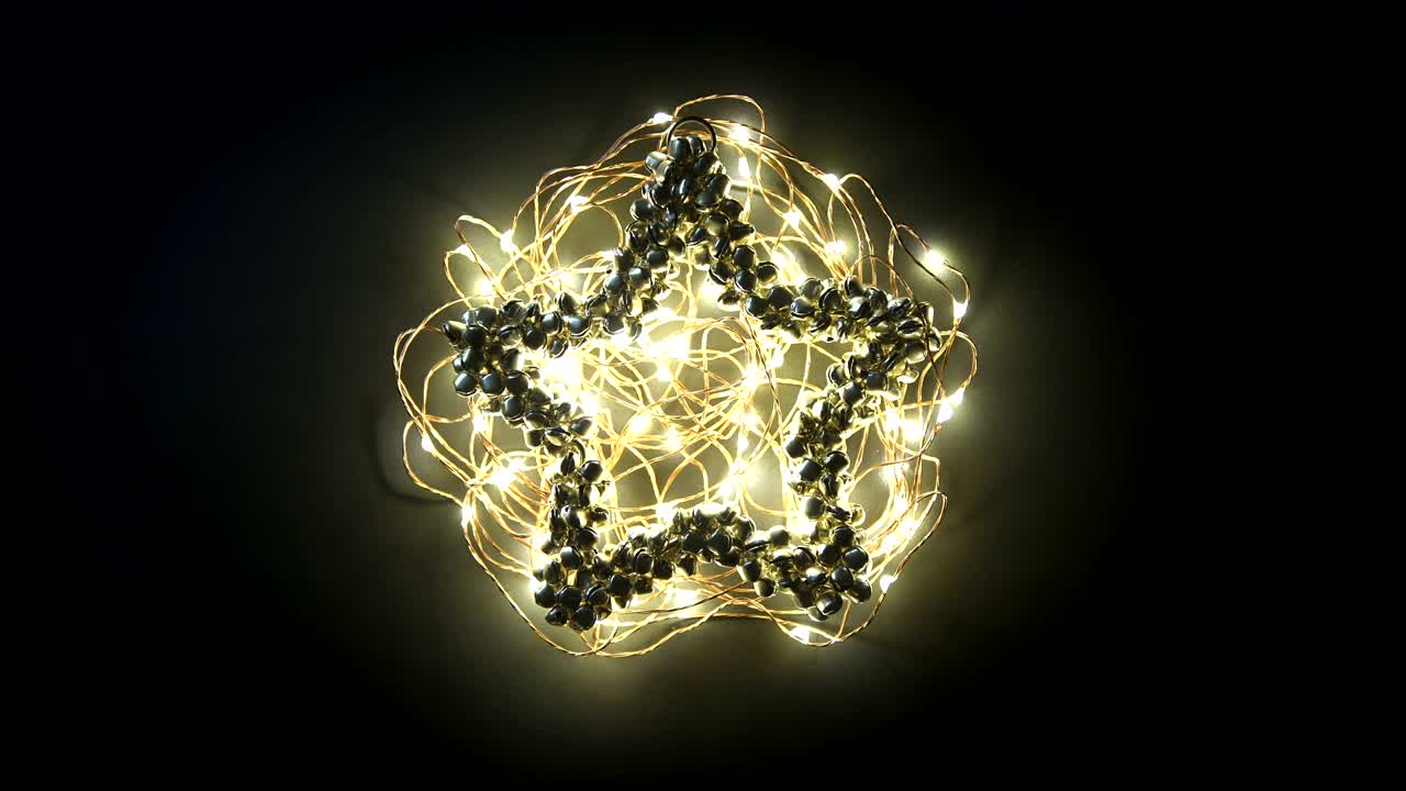 tarjeta de felicitaciones de video de bucle con feliz año nuevo escribiendo animación en una guirnalda amarilla brillante en la decoración de campana de metal en fondo oscuro