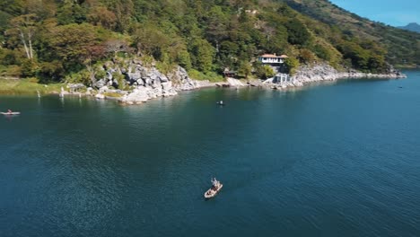 aerial drone shot of a fisherman paddling on a boat in lake atitlan, guatemala