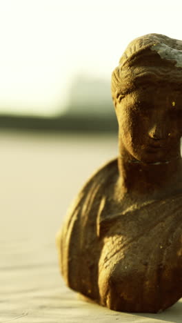 ancient sculpture on sandy beach during golden hour creates serene atmosphere