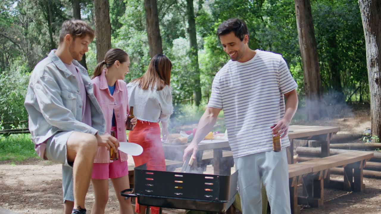 Youngsters enjoying summer bbq in forest. Group friends grilling food cooking