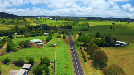 aerial view of scenic country road with vehicle traveling in atherton tablelands region, queensland, australia - drone shot