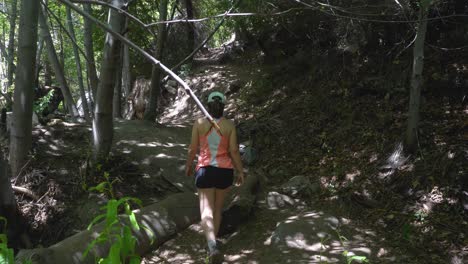 young woman hiking up a shaded trail slow motion