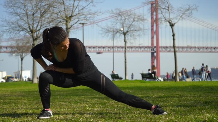 Focused sporty girl stretching on green lawn