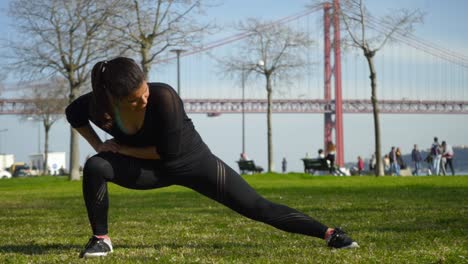 Chica-Deportiva-Enfocada-Estirándose-En-El-Césped-Verde