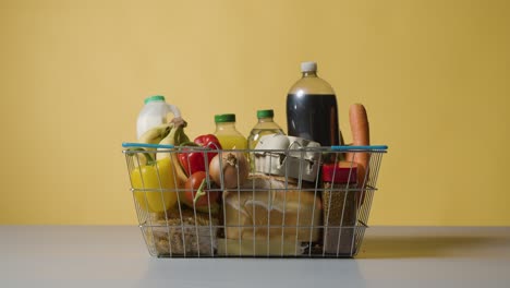 studio shot of basic food items in supermarket wire shopping basket 1