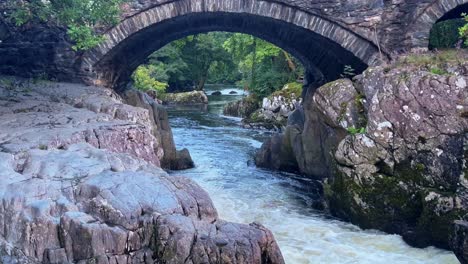 el histórico puente de piedra pont y pair cruza el río conwy en betws-y-coed, gales.